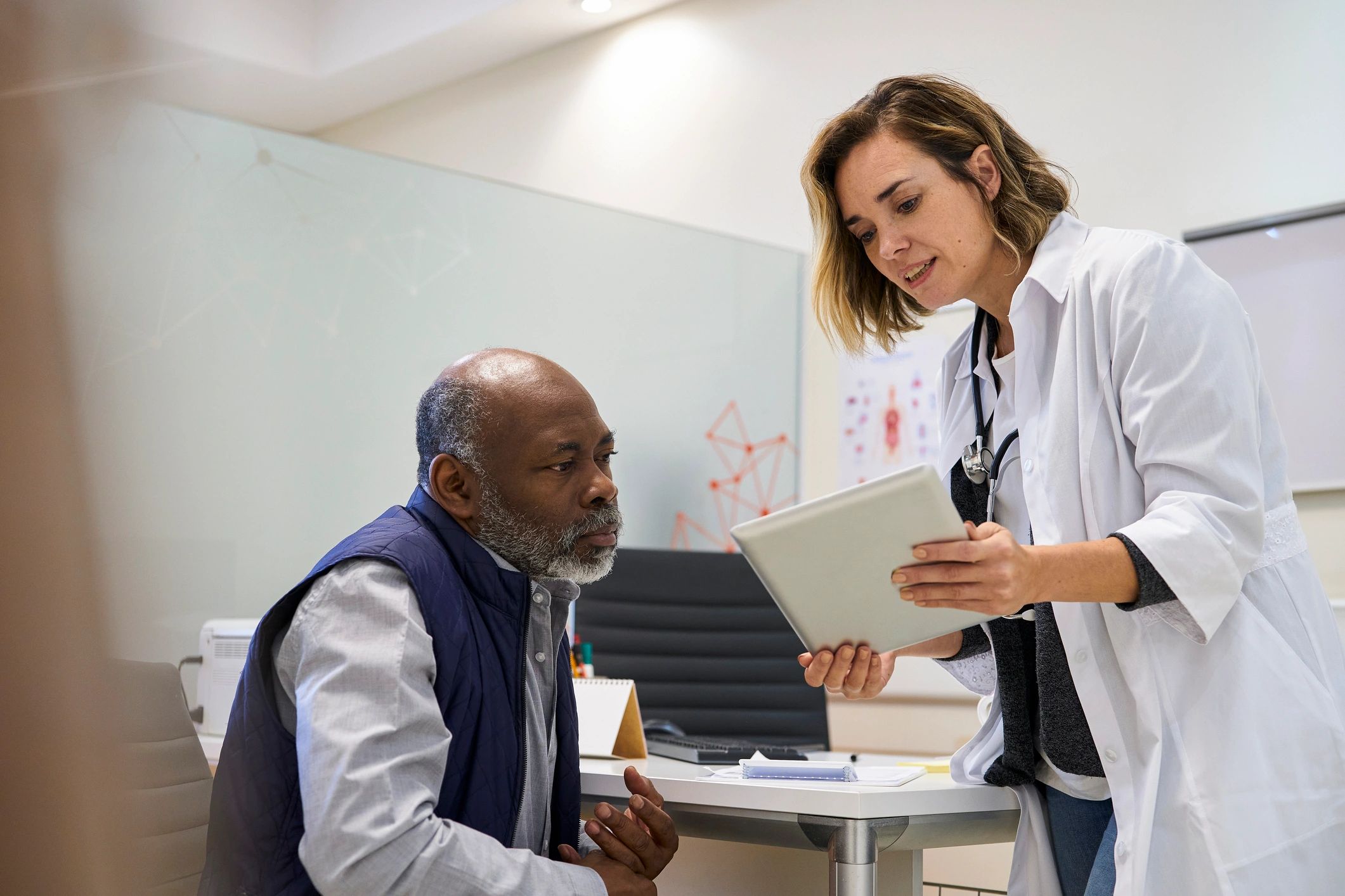 Doctor reviewing care information with a patient using a digital tablet