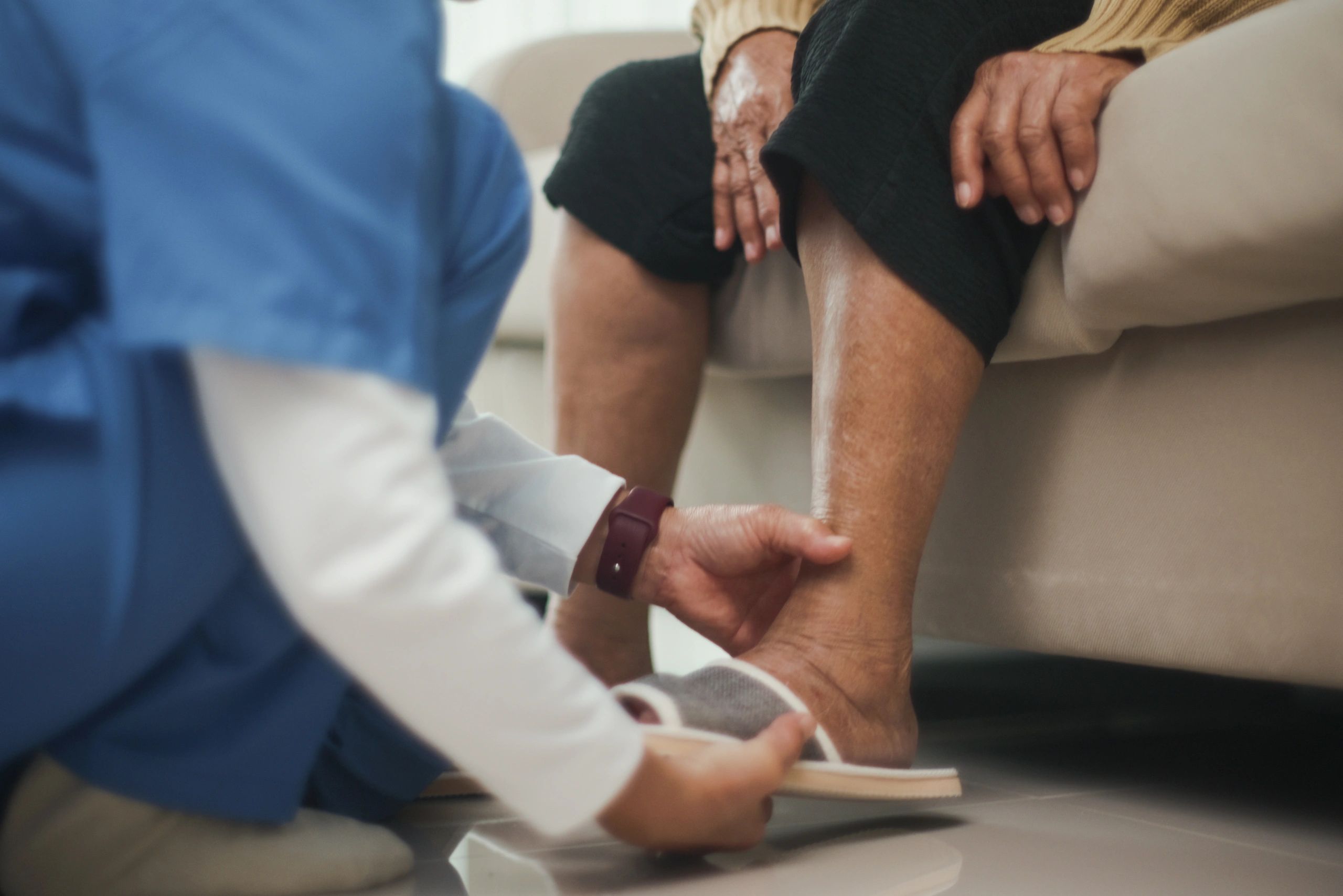 Clinician assisting with footwear and foot care for a senior resident